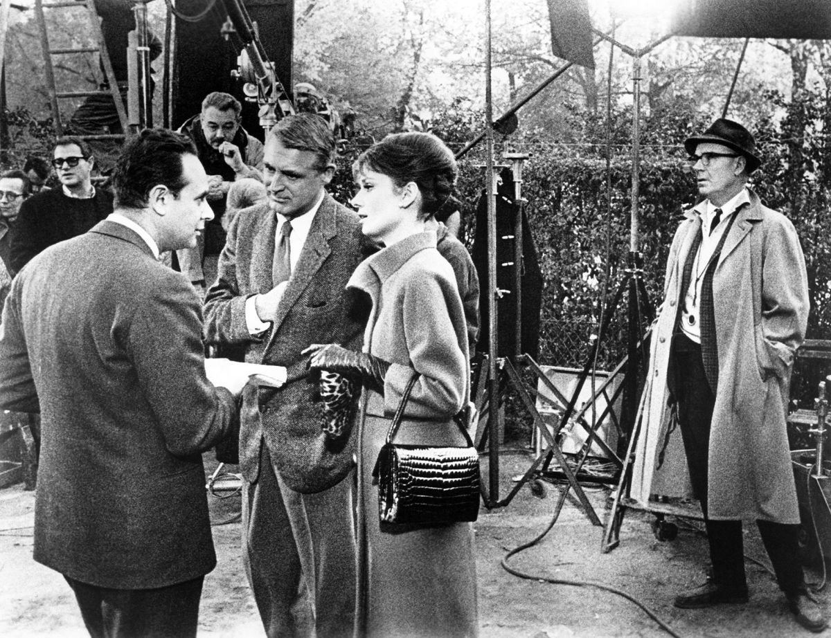 Cinematographer Charles B. Lang, Jr., ASC (far right) looks on as producer-director Stanley Donen (left) discusses upcoming action with Grant and Hepburn on a Paris location. (Photo courtesy of Everett Collection)