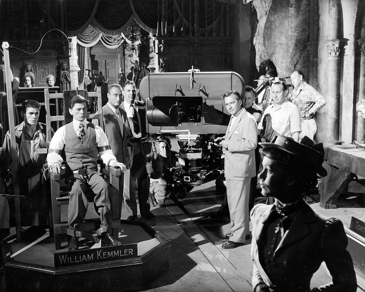 Actors Charles Bronson (far left) and Phyllis Kirk (foreground) are positioned for a take during the production. Warner Bros. still photographer Jack Woods snapped this shot as the Natural Vision camera unit — designed by Milton Gunzberg — was about to roll. Director André De Toth (left of camera, in white vest, next to studio exec Jack M. Warner) was blind in one eye and unable to actually see his film’s 3D effects. To that end, he relied on ASC cinematographers J. Peverell Marley and Robert Burks (right, in front of the camera), operator Howard Schwartz (far right, in white shirt), and 3D consultant Lothrop B. Worth (crouching under camera), both of whom later became Society members.