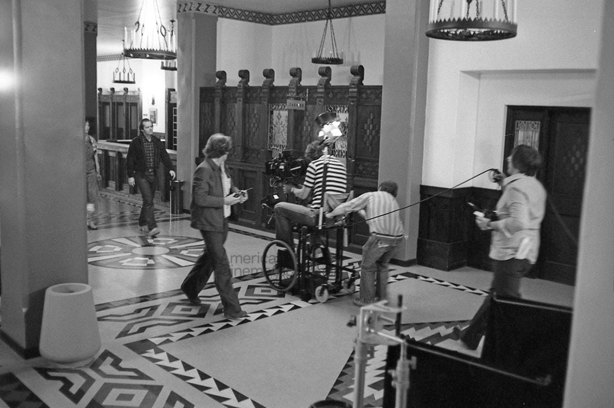 A modified wheelchair served as a rolling camera platform for the Steadicam. In this photograph, it moves ahead of Jack Nicholson, rolling over carpets and doorsills without bumps in the shot. The wheelchair also came in handy for following Danny peddling his plastic “Big Wheel” through the giant interconnected sets.