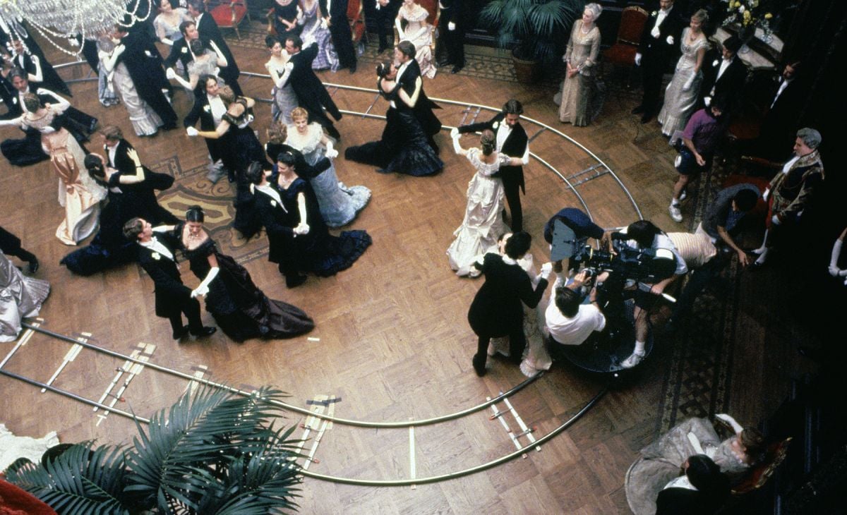 The camera crew dollies around costumed dancers during an elaborate ballroom sequence while filming the elegant, lavishly detailed drama The Age of Innocence