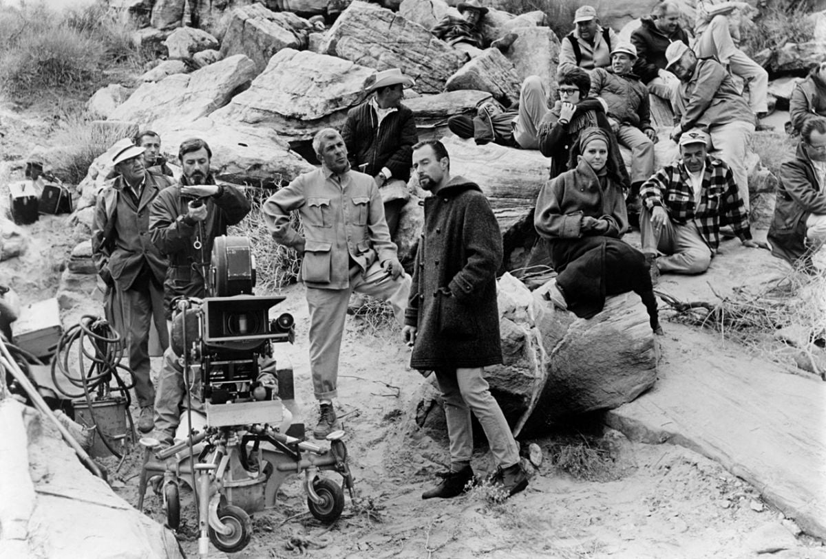 Shooting on location in the Valley of Fire in Nevada, Hall (behind the camera) takes a light reading while director Richard Brooks (in light suit, center) prepares to stage a rehearsal.