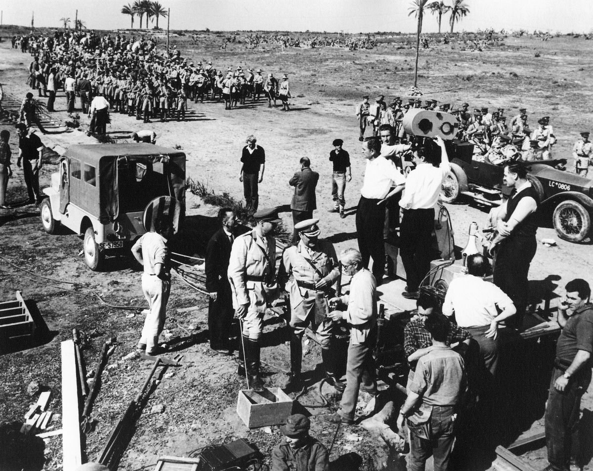 On location, director David Lean stands on the platform in front of the 65mm Super Panavision 70 camera and takes in all in while two assistants behind him set a shot on the oncoming parade. Just in front of Lean, to his left, is cinematographer Freddie Young, BSC (wearing white shirt). Young earned the 1963 Academy Award for his masterful camerawork, among other honors.