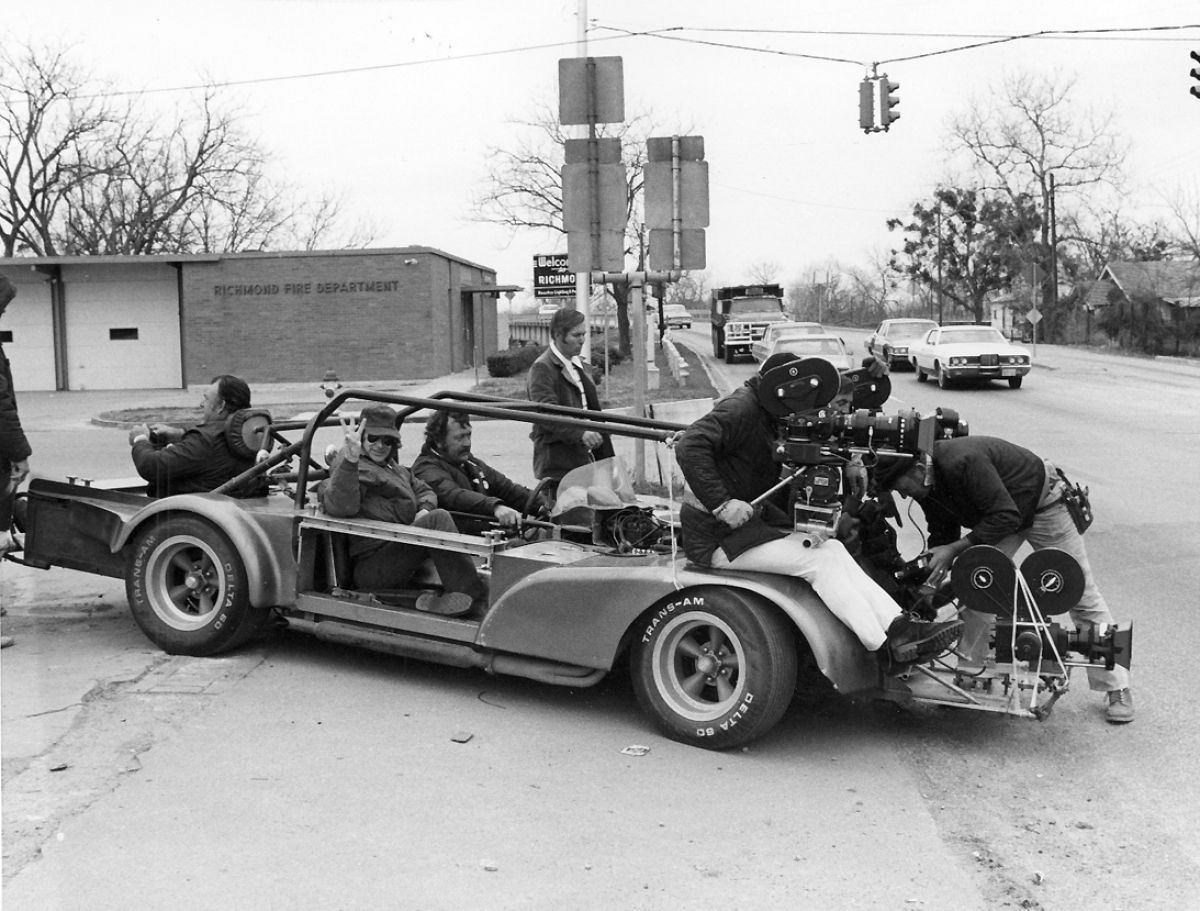 Driver Pat Hustis, with Spielberg at his side, prepares to make a wild run in the "Bullitt" car, so-called because it was the vehicle originally designed to shoot the wild chase sequence in the film Bullitt. Operator Sven Walnum and Zsigmond (glimpsed between the two magazines) are strapped in behind two “fender” cameras in preparation for the run. A third camera has been installed for remote shooting from low camera platform on front of the vehicle.